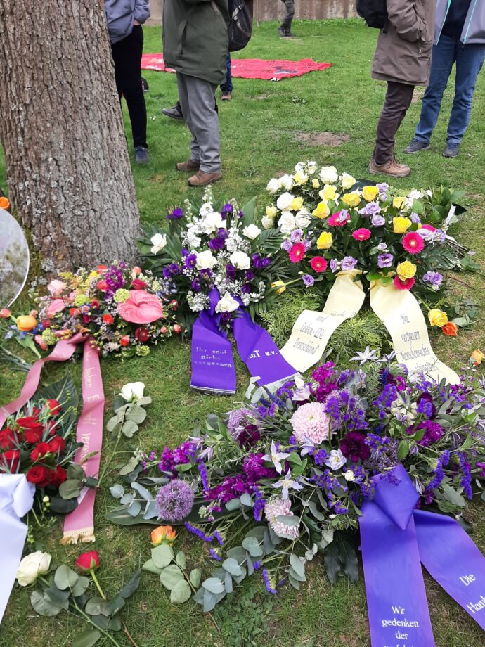 Gedenkfeier in Ravensbrück - Blumenkränze unter einem Baum