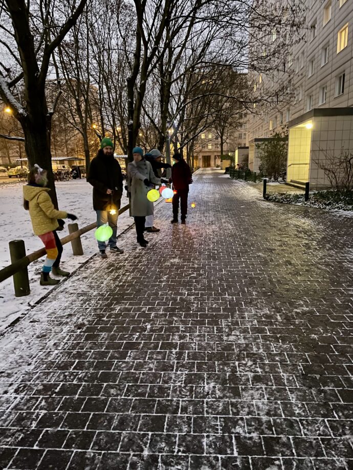 Eine Gruppe von Menschen mit Laternen auf der Straße im Winter.