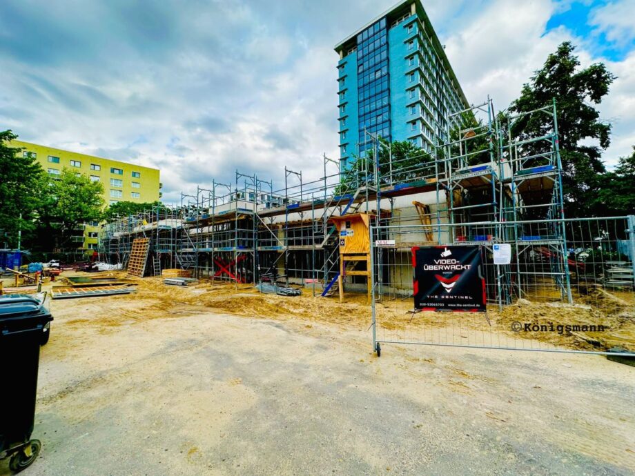 Bild auf die Baustelle in Richtung Bezirksamt. Gerüste sind vor dem fertigen Erdgeschoss aufgebaut.